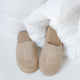 Badslippers in latte met DOUXE logo, liggend in een dekbed